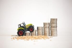 Un tracteur jouet qui gravit un escalier formé de pièces de monnaie empilées.