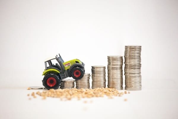 Un tracteur jouet qui gravit un escalier formé de pièces de monnaie empilées.