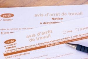 Formulaires français d’« avis d’arrêt de travail » sur lesquels repose un stylo.