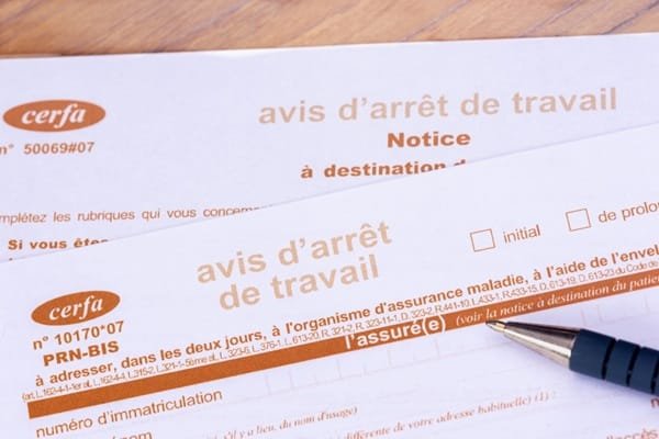 Formulaires français d’« avis d’arrêt de travail » sur lesquels repose un stylo.