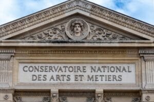 Fronton en pierre du Conservatoire national des arts et métiers, orné d'un médaillon central représentant un visage sculpté.