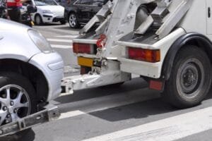 Une dépanneuse remorquant une voiture argentée dans une rue de la ville.