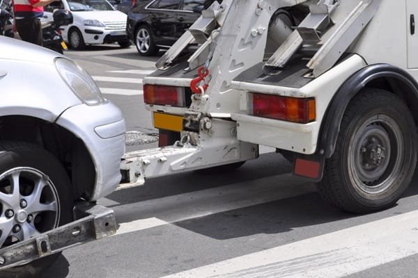 Une dépanneuse remorquant une voiture argentée dans une rue de la ville.