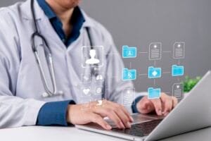 Un médecin en blouse blanche tapant sur un ordinateur portable, avec une interface numérique composée d'icônes médicales et de dossiers de patients flottant au-dessus du clavier.
