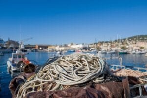 Une corde blanche enroulée sur le pont d'un bateau dans un port.