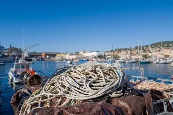 Une corde blanche enroulée sur le pont d'un bateau dans un port.