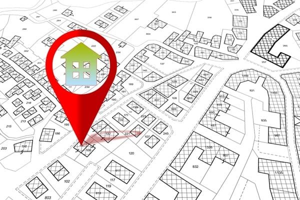 Une icône représentant une punaise rouge avec le dessin d'une maison, centrée sur une parcelle figurant sur un plan cadastral.