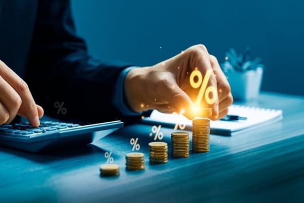 Une personne empilant des pièces de monnaie sur lesquelles figurent des symboles de pourcentage lumineux, tout en utilisant une calculatrice.