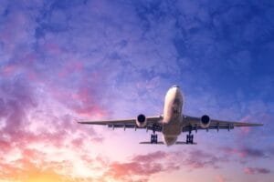 Un avion de ligne en vol sur fond de ciel nuageux au coucher du soleil.