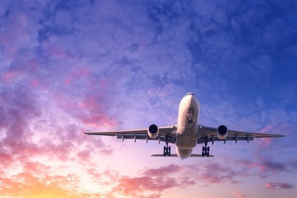 Un avion de ligne en vol sur fond de ciel nuageux au coucher du soleil.