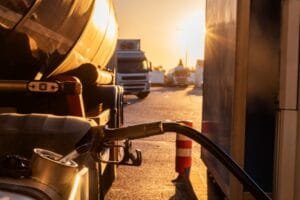 Une buse de ravitaillement en gaz alimentant un camion-citerne dans une station-service au coucher du soleil.