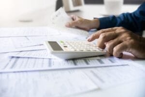 Une personne utilisant une calculatrice tout en examinant des documents financiers.