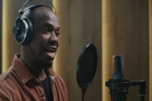 Un homme portant un casque parle dans un micro de studio équipé d'un filtre anti-pop.