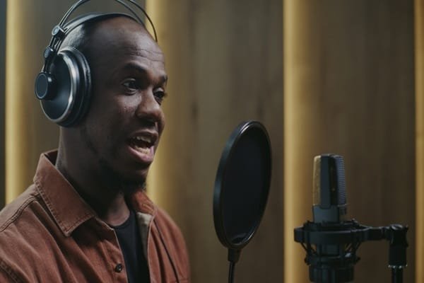 Un homme portant un casque parle dans un micro de studio équipé d'un filtre anti-pop.